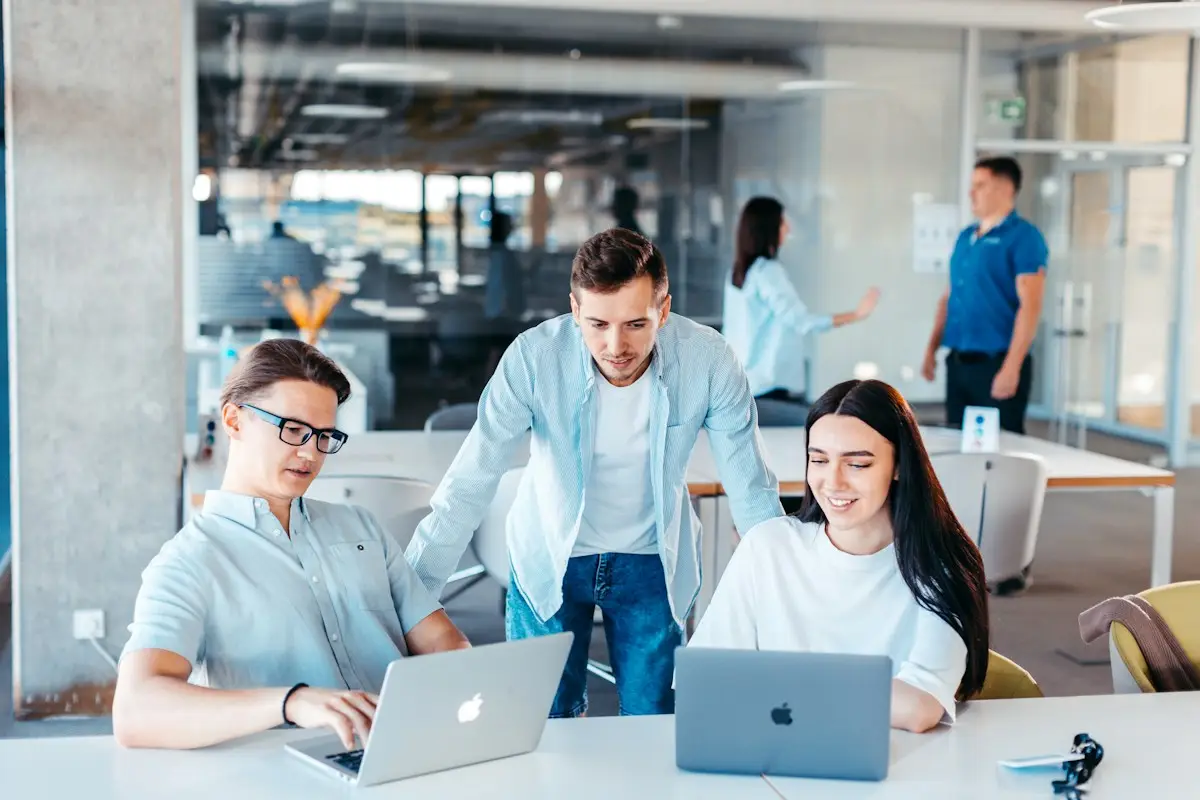 Kleines Büroteam bespricht sich an Laptops
